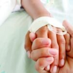 Una persona sostiene la mano de otra mientras se somete a un tratamiento médico